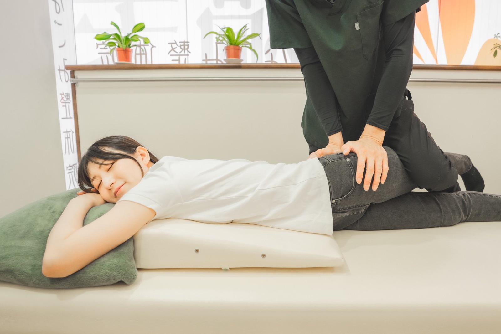 院長が、うつ伏せでリラックスしたお客様の骨盤に両手を当てて調整している様子